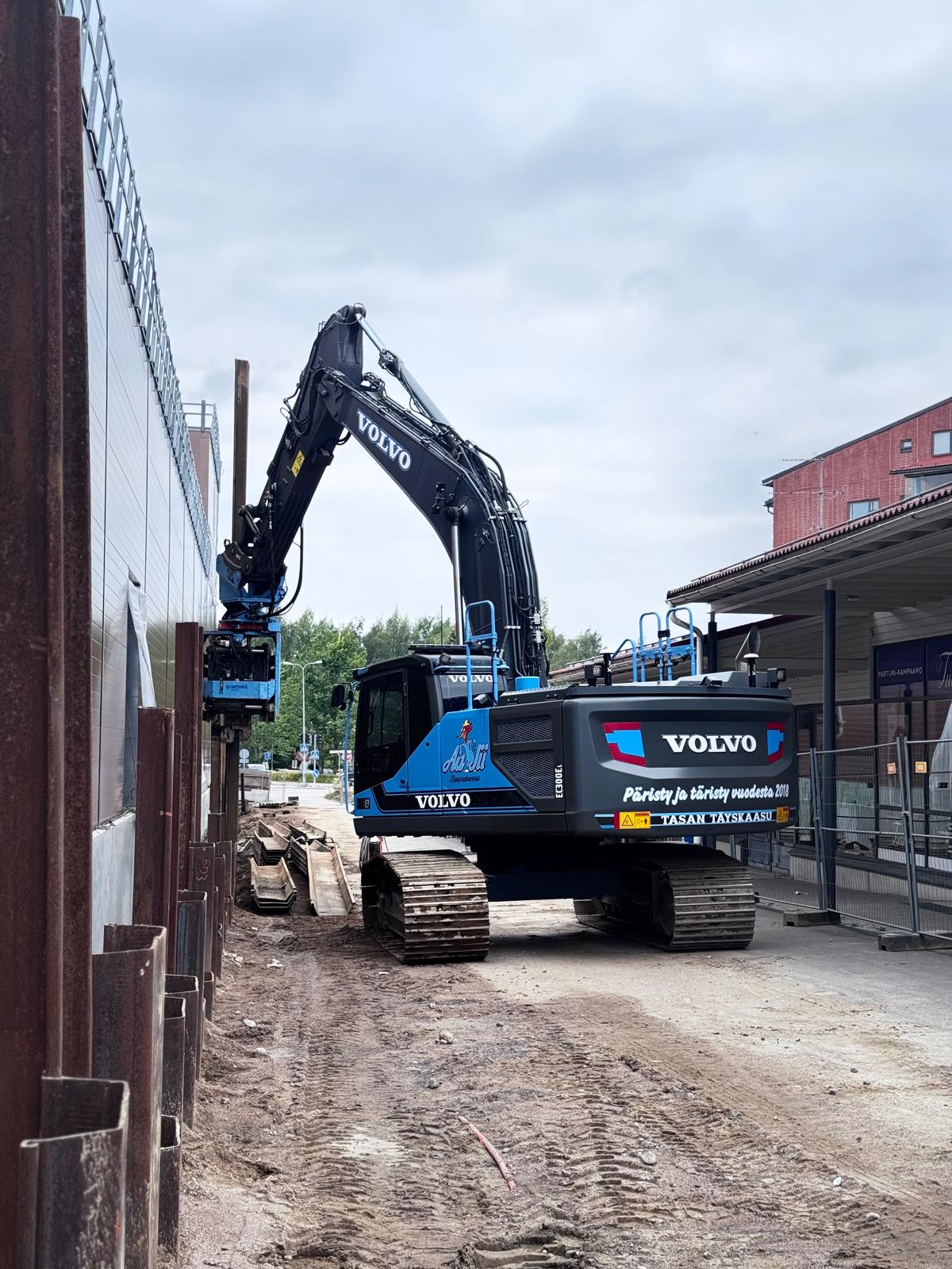 Volvo-kaivinkone asentaa teräspontteja rakennuksen vieressä