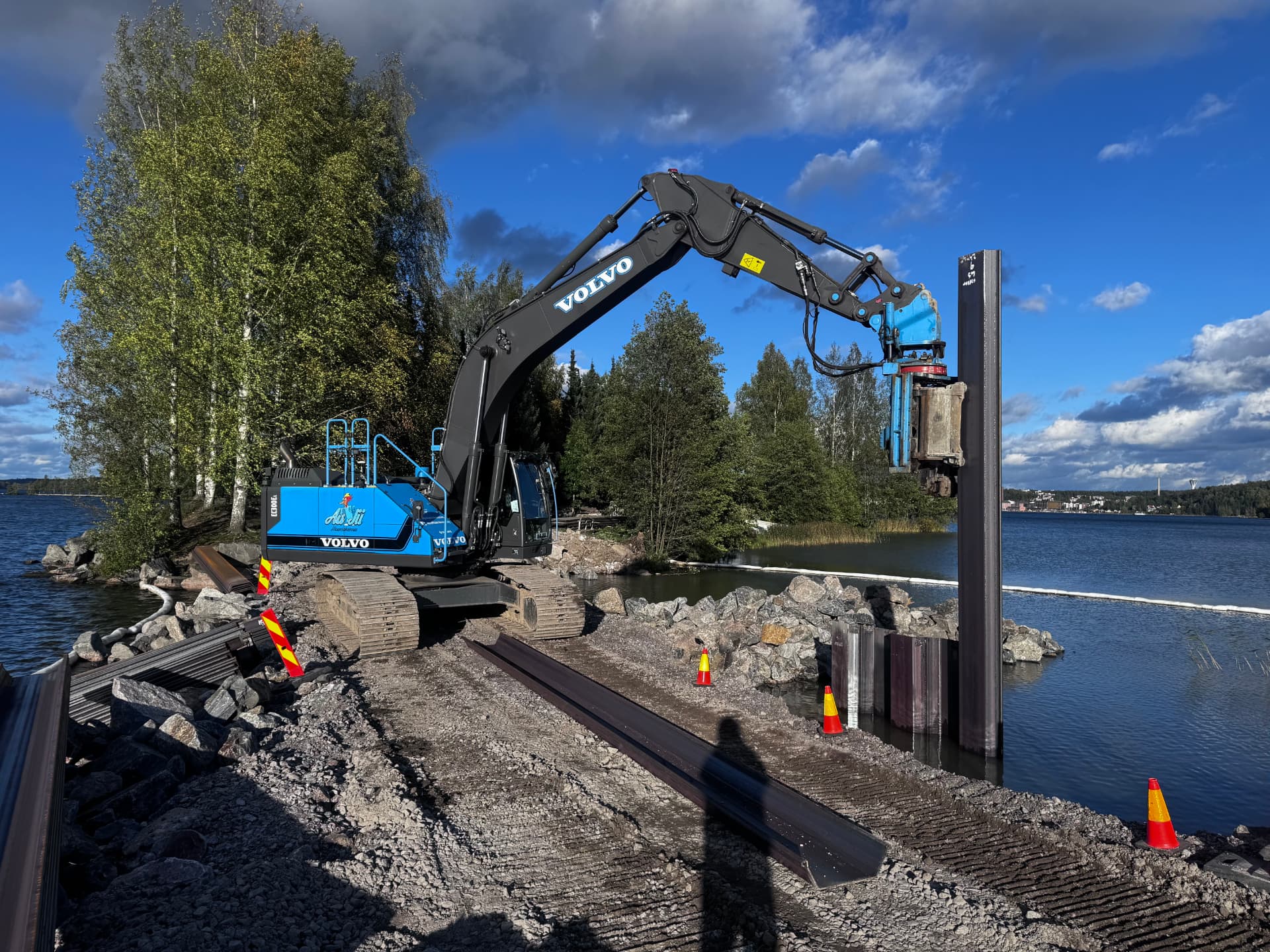 AaJiin Volvo-kaivinkone asentaa teräspontteja Movax-laitteella rantakohteessa
